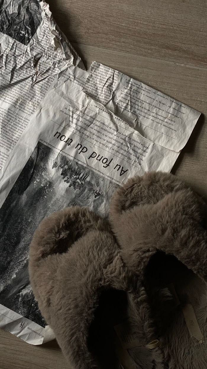 digital Soft brown slippers on a crumpled paper background with subtle text.