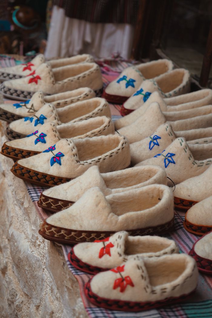 creative A collection of traditional woolen slippers with colorful embroidery displayed at an outdoor market.