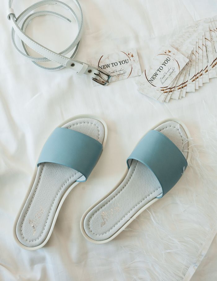mobile-01 A stylish flat lay featuring blue sandals and white leather belt on a white background.